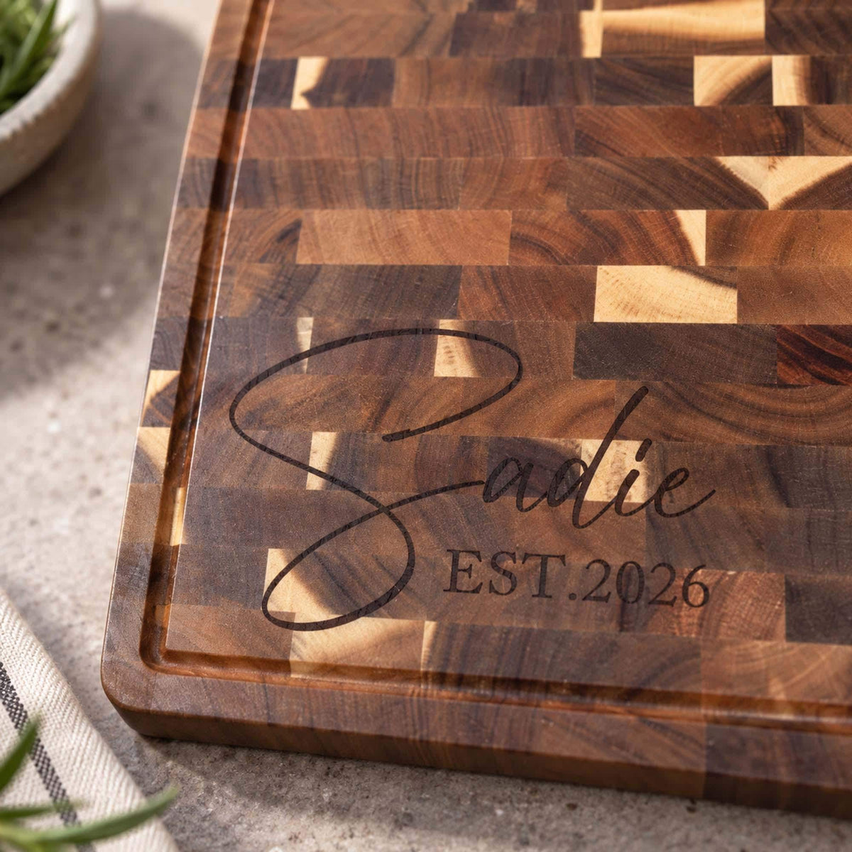 Engraved End-Grain Acacia Chopping Board: close-up of a script name and date engraved on end-grain acacia