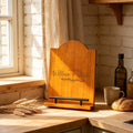 Personalised Acacia Cookbook Stand: personalised acacia cookbook stand engraved with two names on a kitchen worktop